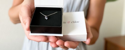 woman holding Cate Chloe Necklace next to box