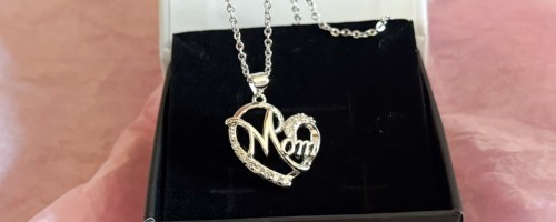 person holding cate & chloe persephone mom necklace in front of box with pink tissue paper