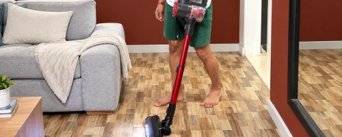 Man using lighted cordless vacuum in living room with wooden floor