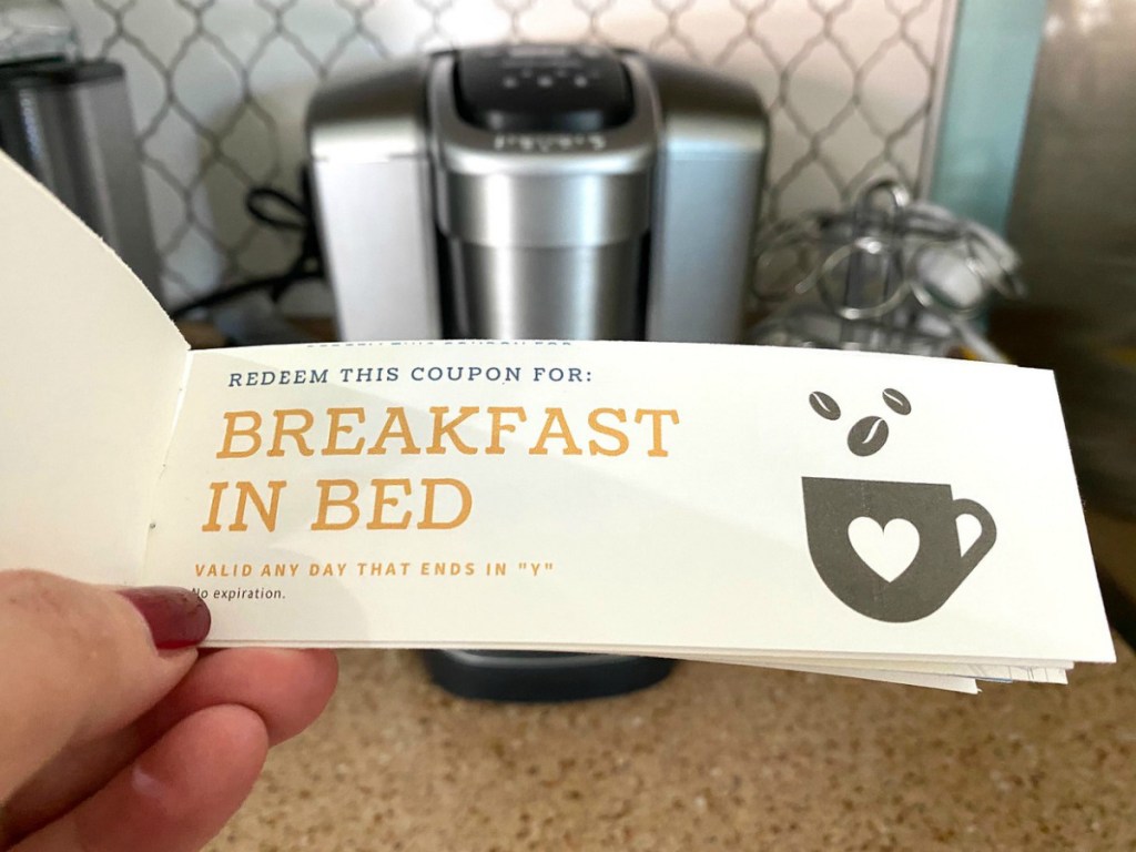 Woman holding a coupon book in front of a coffee maker