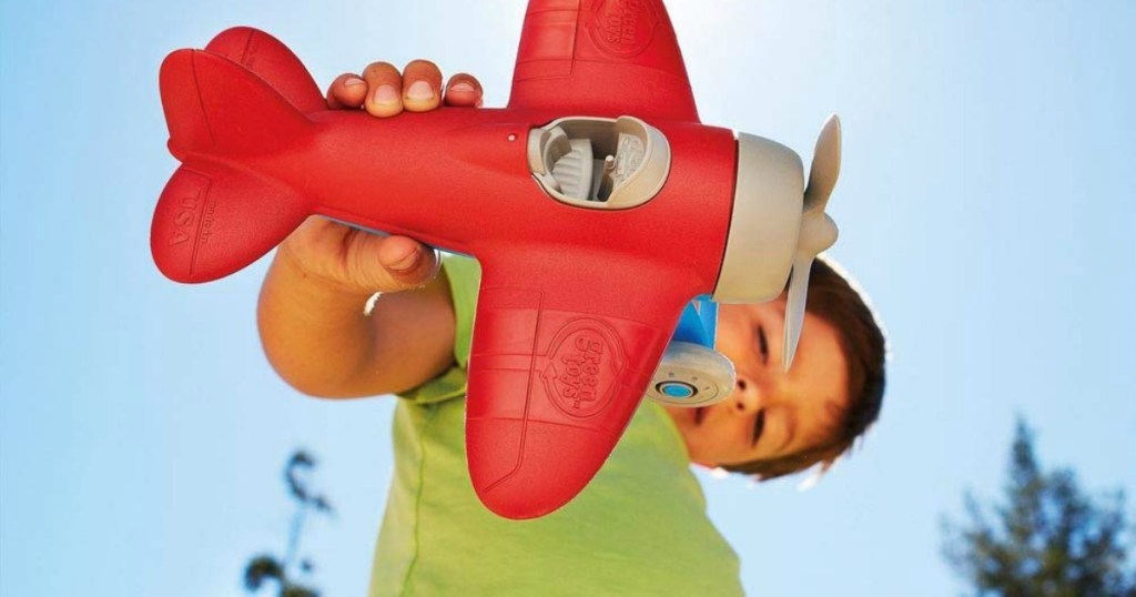 boy flying Green Toys red and gray airplane