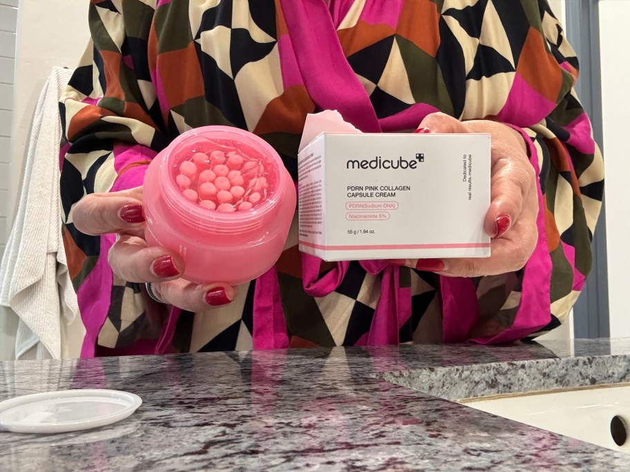 womans hand holding a jar of moisturizer