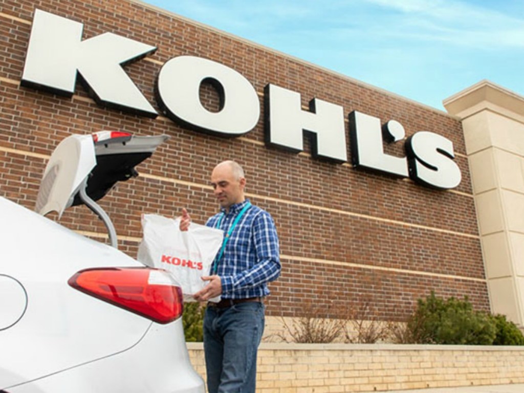 Kohl's employee placing a kohl's shopping bag into the trunk of a car