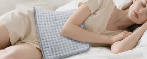Woman lying down with eyes closed with large heating pad over abdomen
