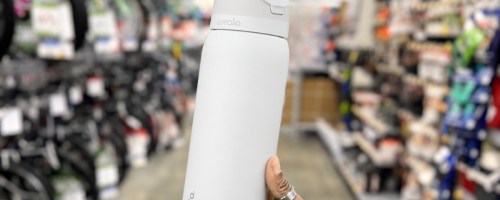 person holding white owala water bottle in store
