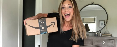 Woman with excited smile holding a large Amazon shipping box