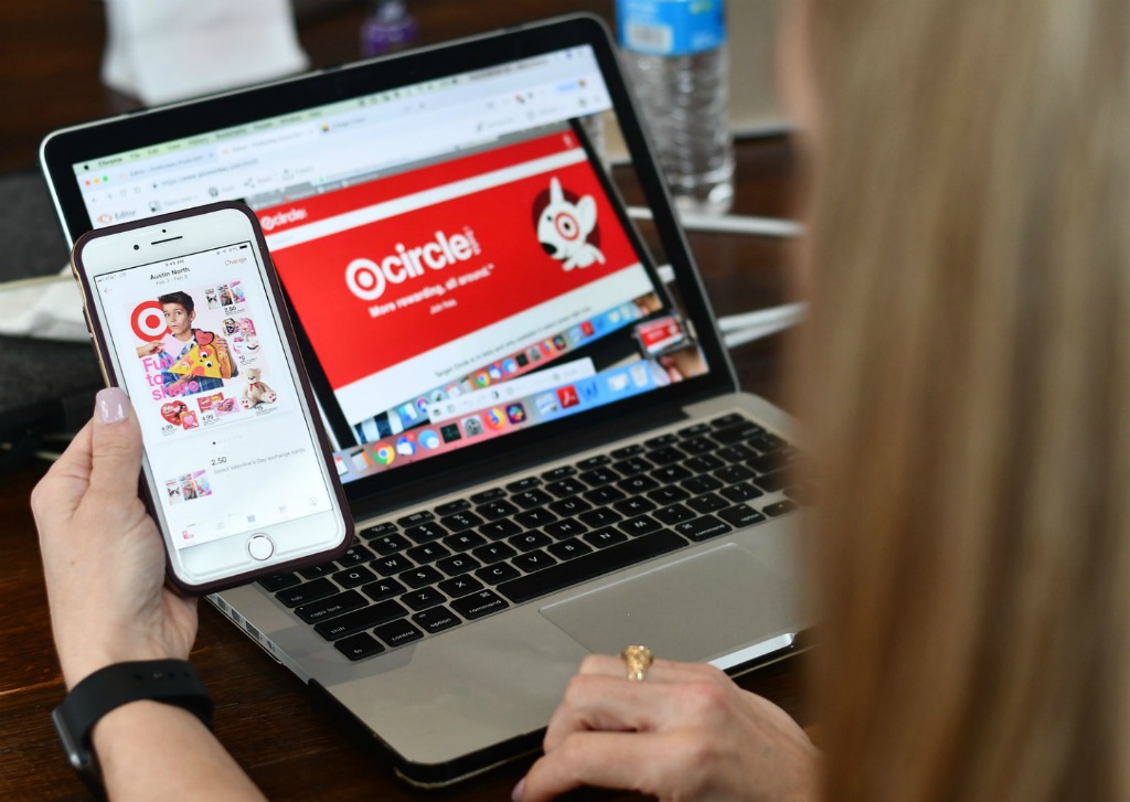 woman looking at Target app on her cellphone near a laptop