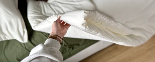 person holding white comforter on bed