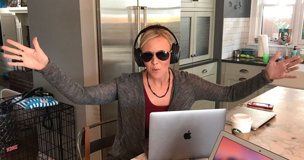 woman wearing headphones in front of laptop in kitchen