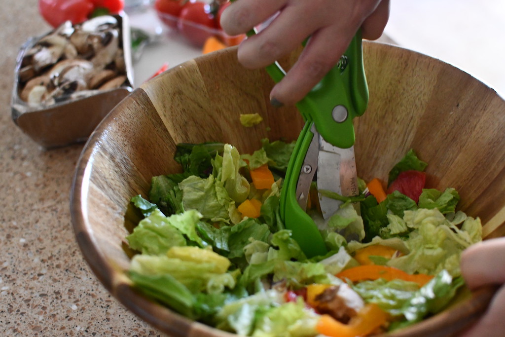 chopping salad with scissor tongs 