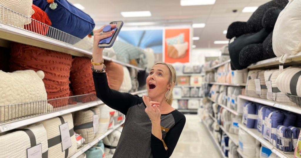 woman holding up cell phone in store bedding aisle