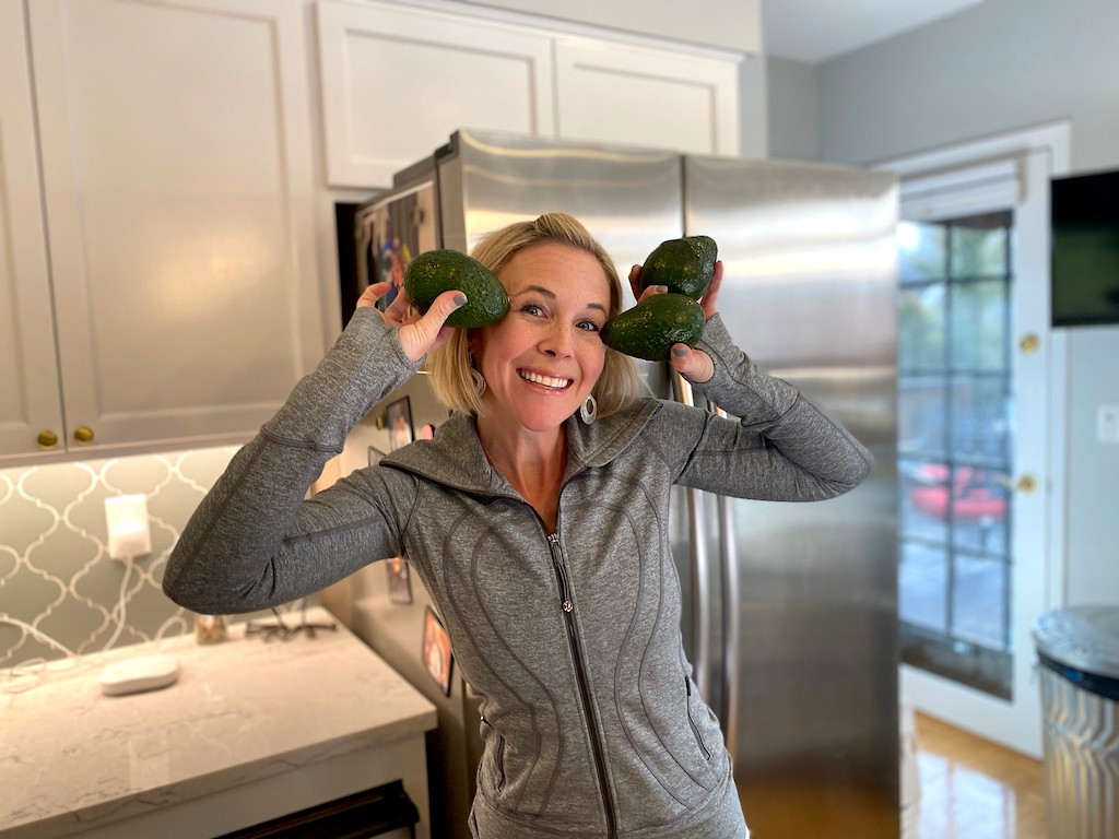 woman holding up avocados in kitchen