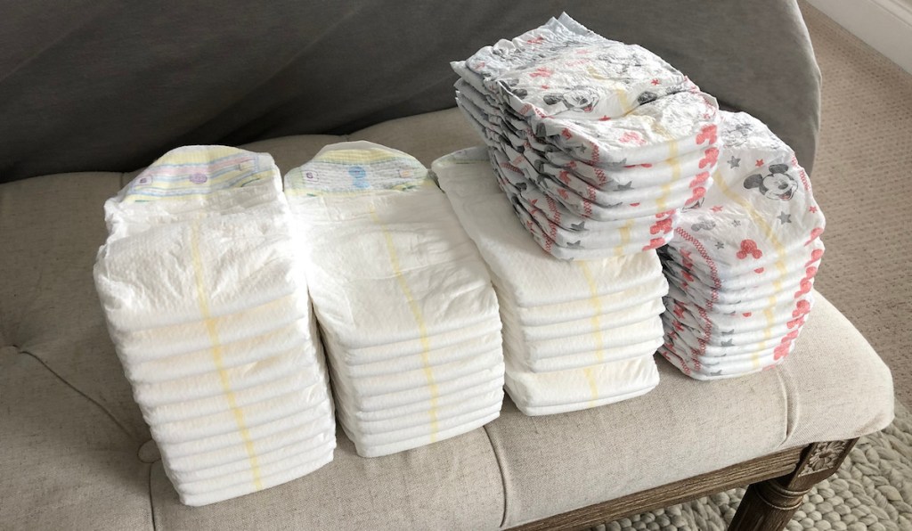 stacks of white and mickey mouse diapers on a tufted bench