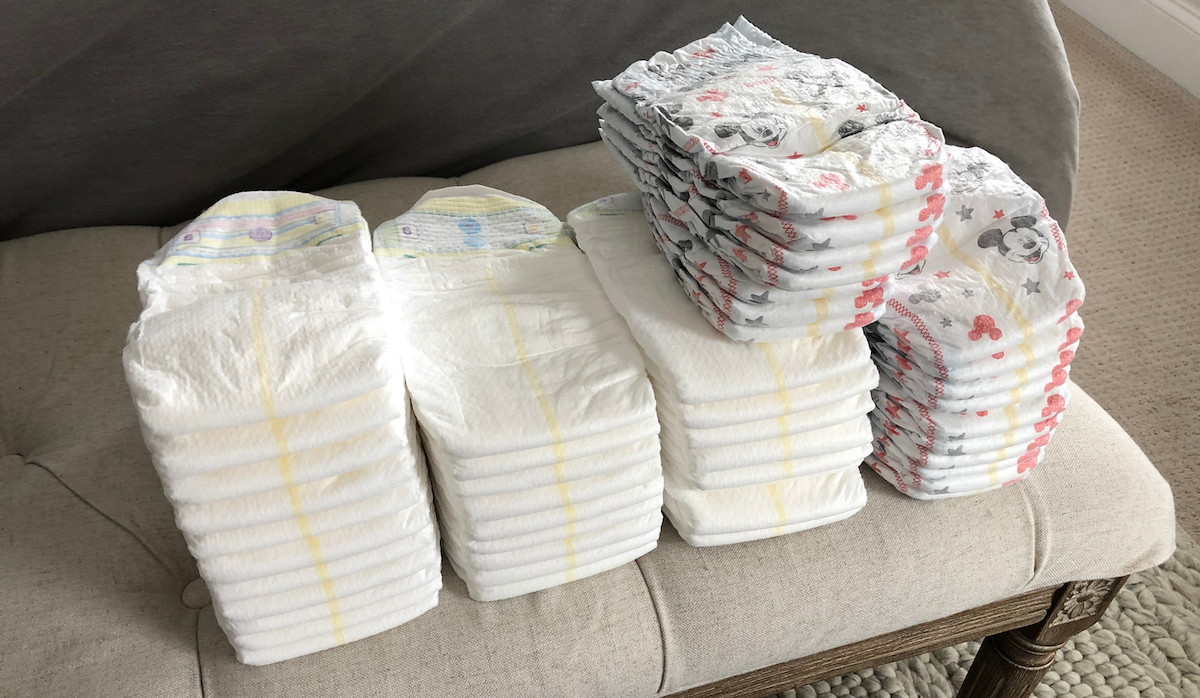 stacks of white and mickey mouse diapers on a tufted bench
