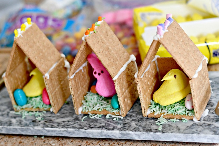 graham cracker houses with Easter Peeps and candy inside, an Easter gingerbread house craft project for kids 