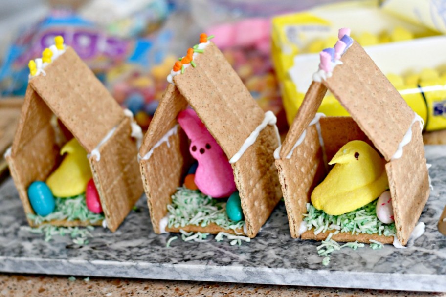 graham cracker houses with Easter Peeps and candy inside, an Easter gingerbread house craft project for kids 