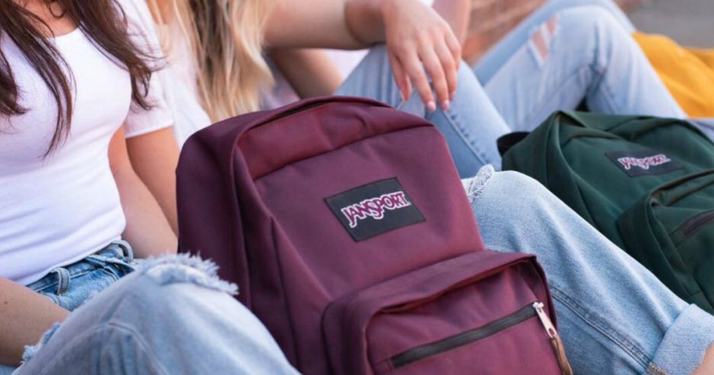 Girls sitting with a purple jansport backpack