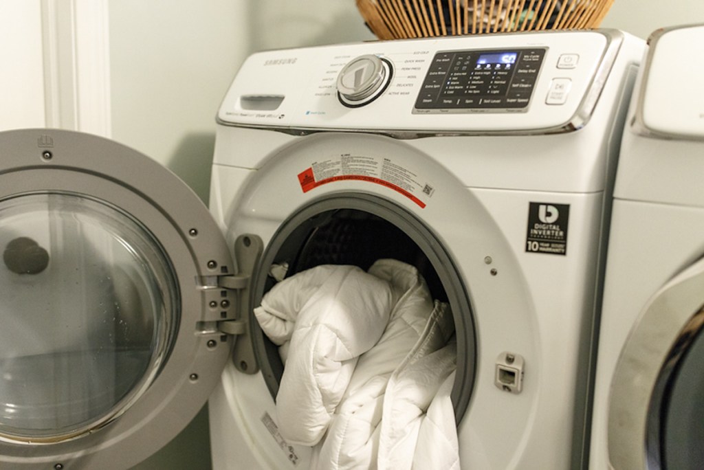 front load washer with white blanket hanging out of it