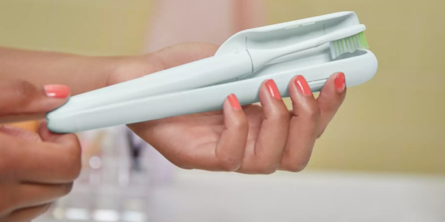 Woman holding light blue, sonicare, Phillips toothbrush