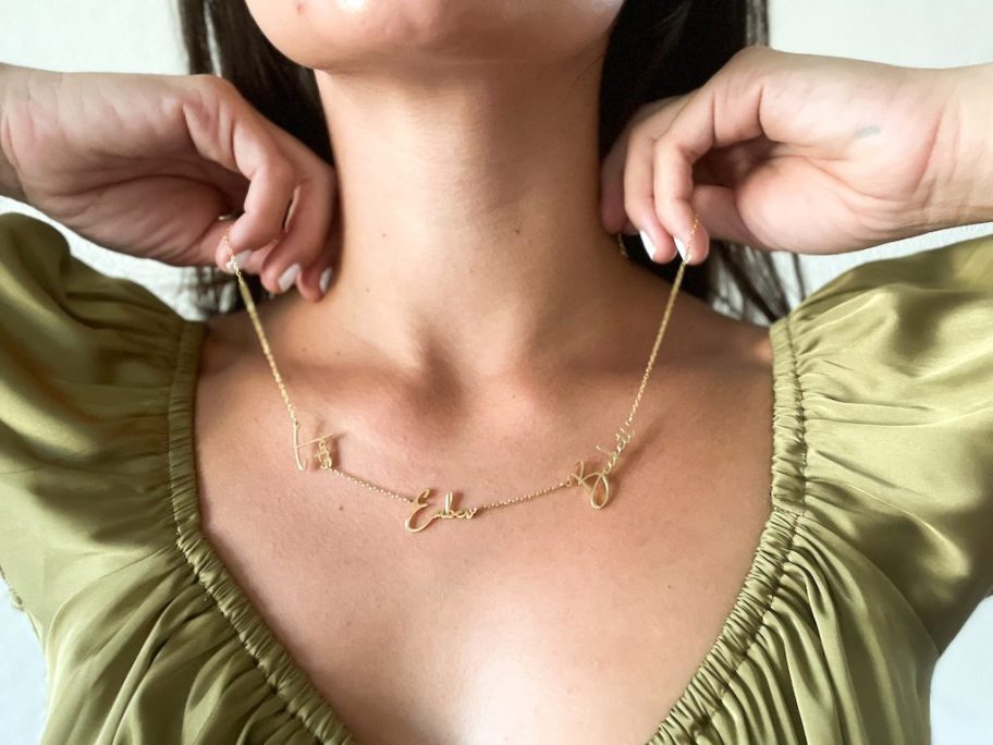 woman wearing gold name necklace with silky green shirt