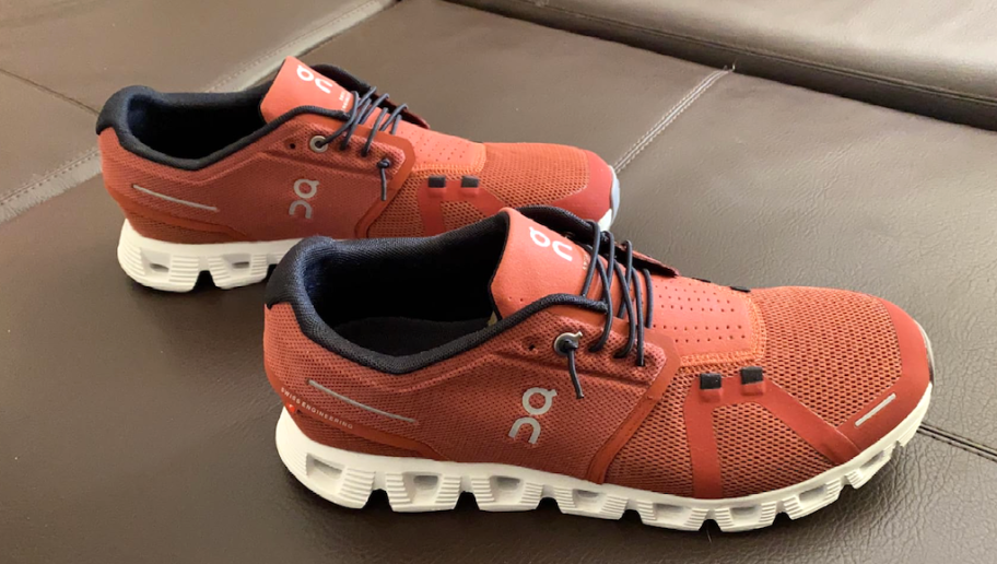 a pair of on cloud orange running shoes