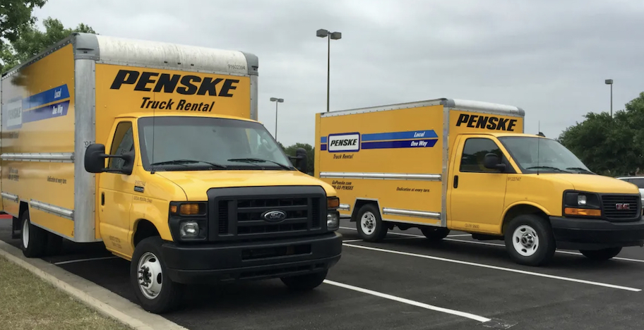 two yellow penske moving trucks in parking lot