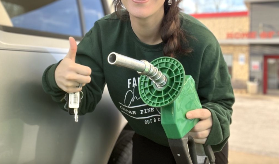 person holding keys in one hand and gas pump in the other