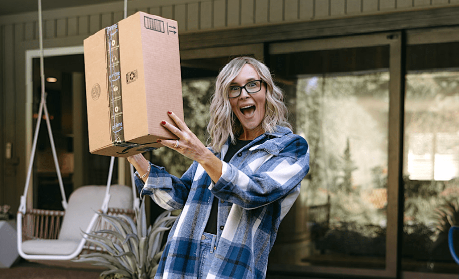 woman holding up amazon box on porch