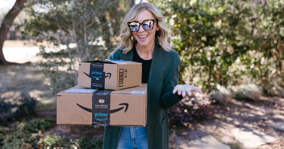 woman holding stack of amazon boxes