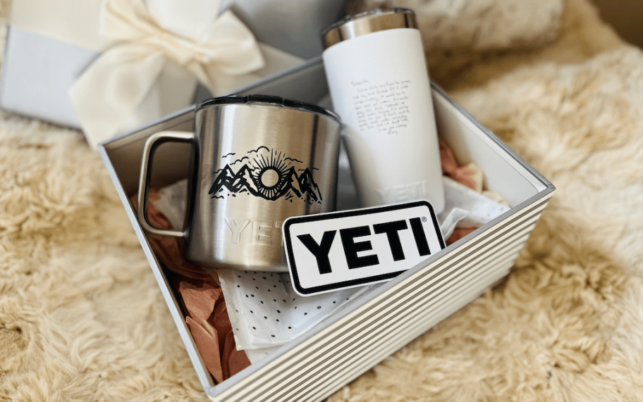 a box with a silver YETI mug with a custom image on it and a white YETI tumbler with a monogram on it