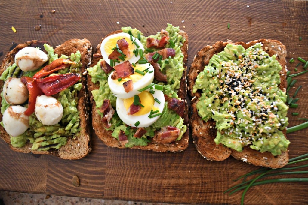 wood board with 3 examples of smashed avocado toast 