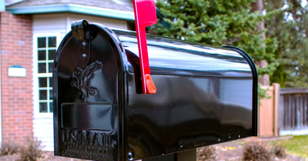 black mailbox outside with raised red flag on side