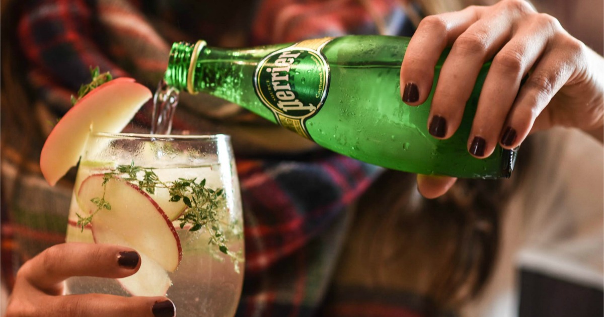 bottle of perrier sparkling water pouring into wine glass with apples