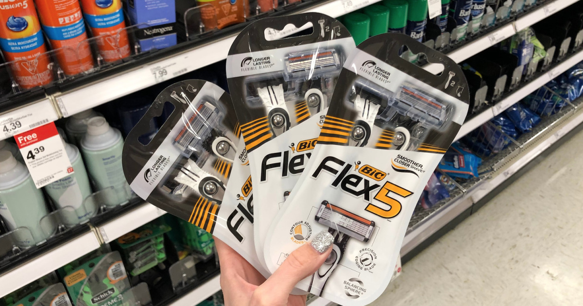 hand holding three packages of razors in front of a store shelf