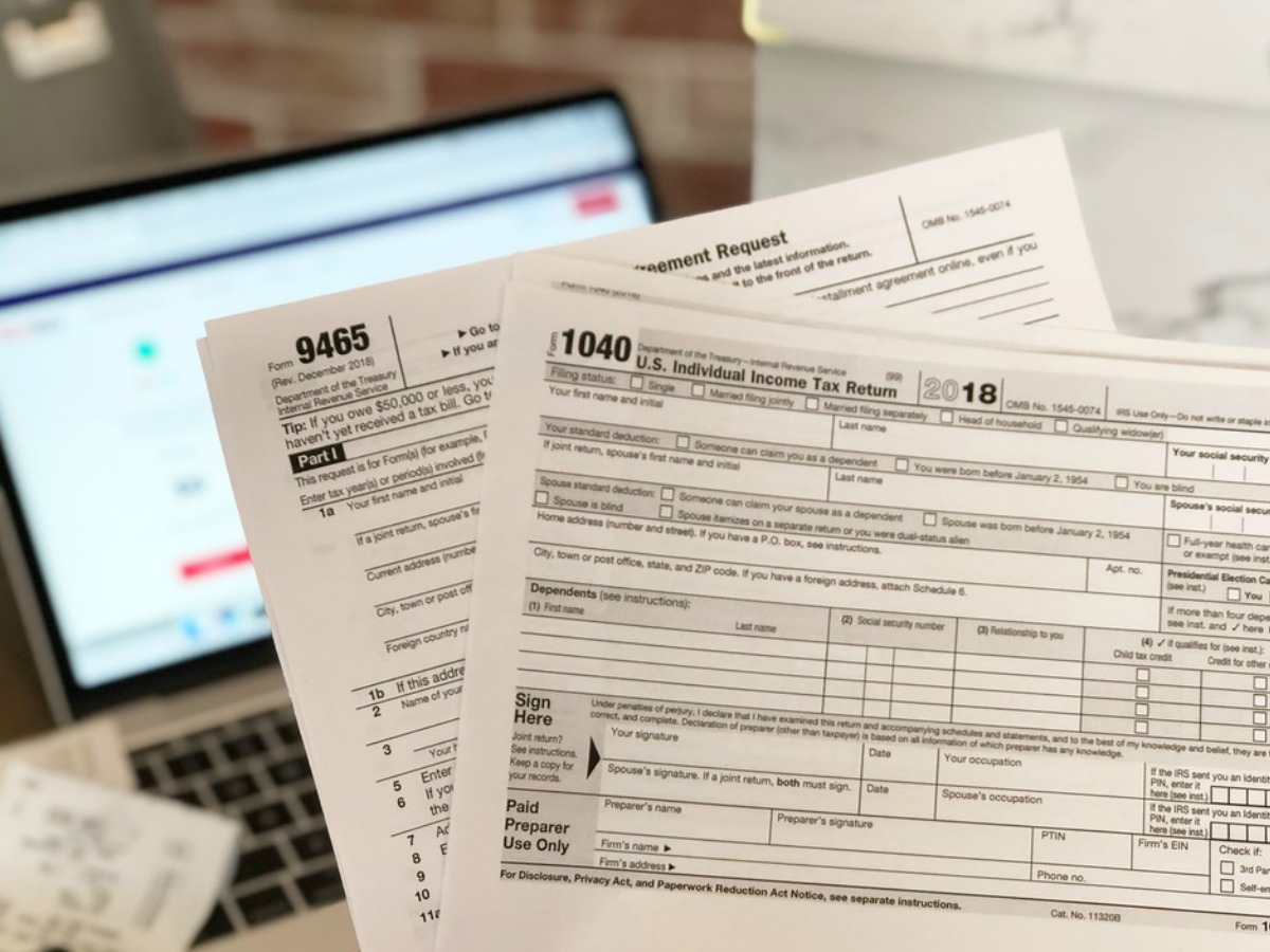 a 1040 and a 9465 tax form in front of a computer screen