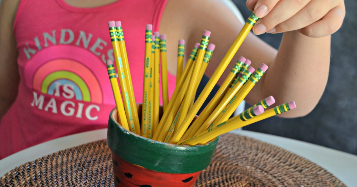 Ticonderoga pencils in cup next to girl