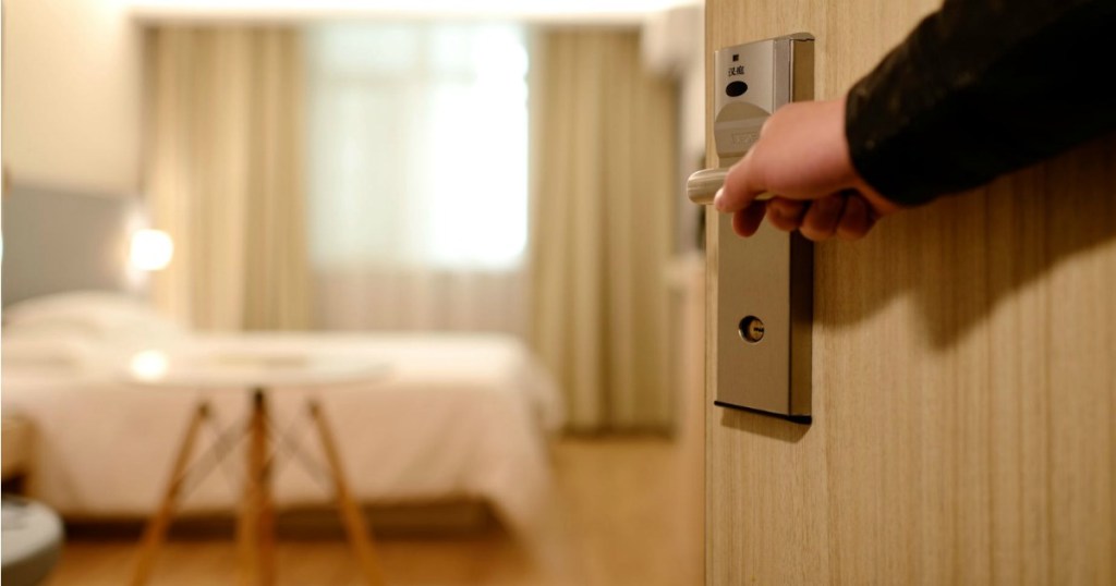 Hand holding a hotel room door open.