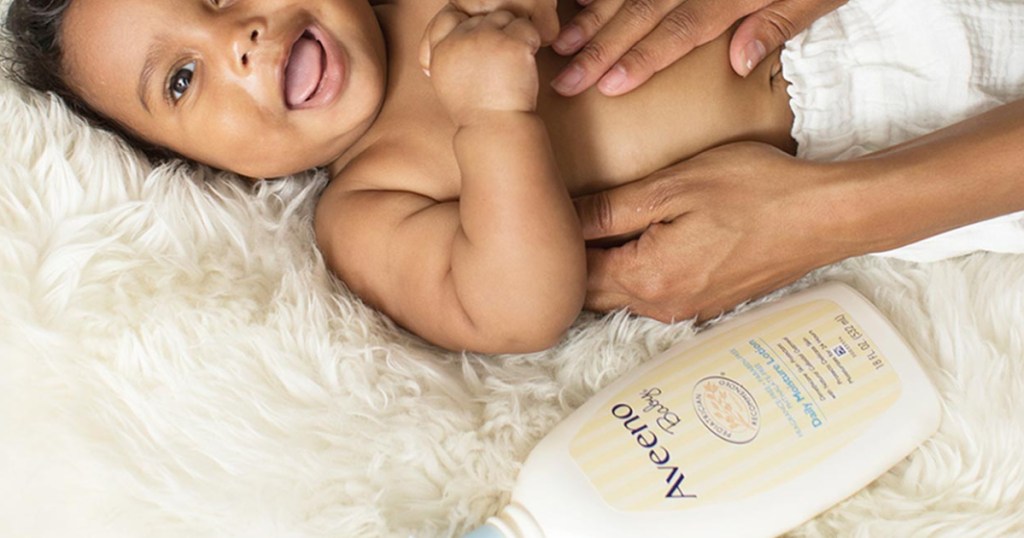 baby laying next to bottle of aveeno lotion