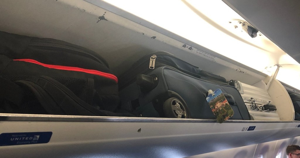 three suitcases luggage in overhead compartment on airplane