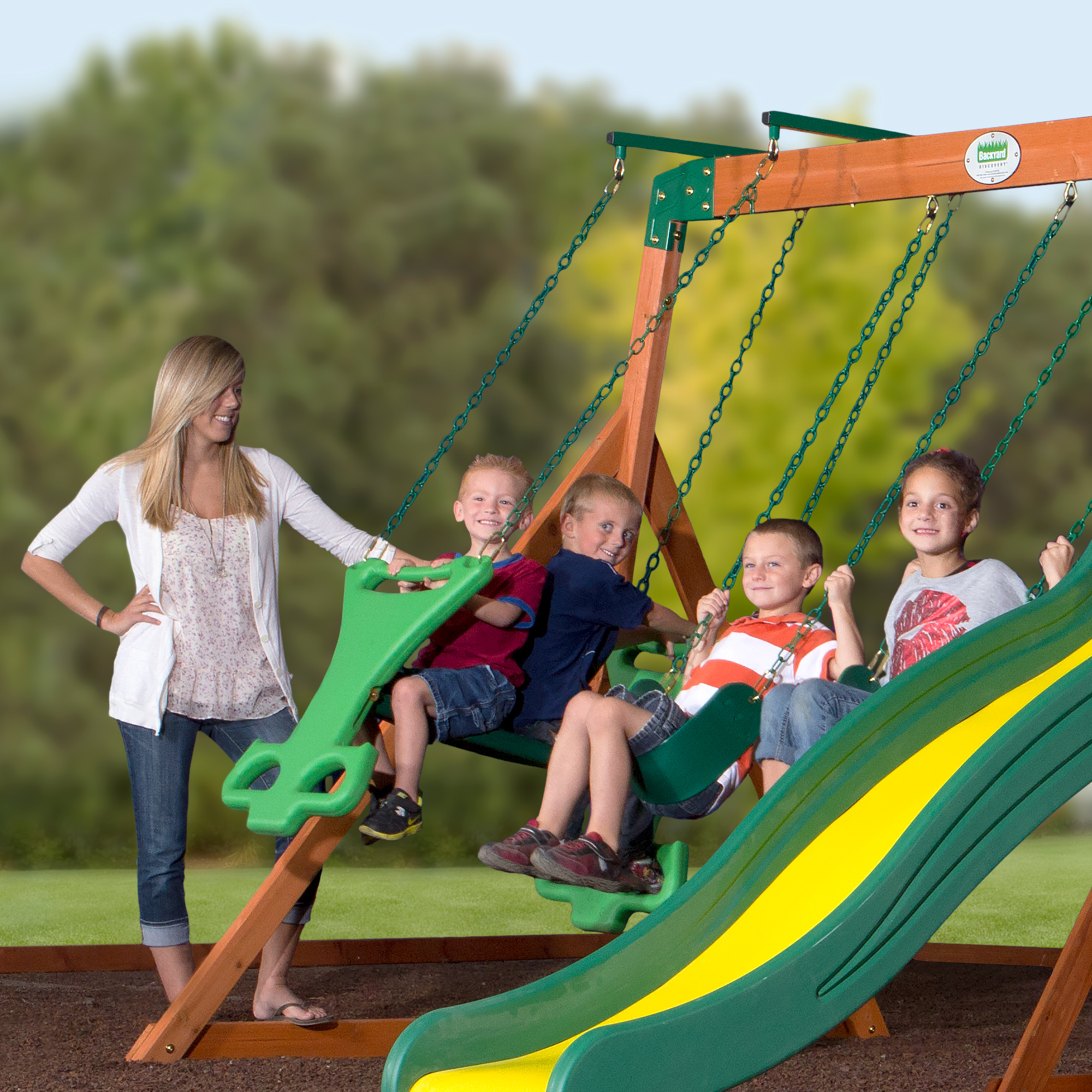 mom with kids playing on a wooden swing set