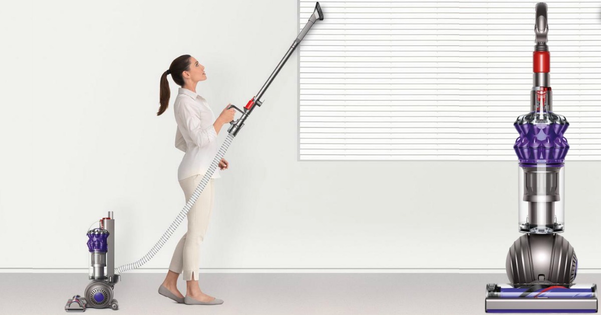 woman using a dyson small ball vacuum to vacuum blinds in living room