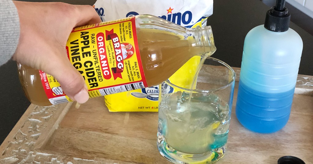 pouring apple cider vinegar into cup for fruit fly trap diy