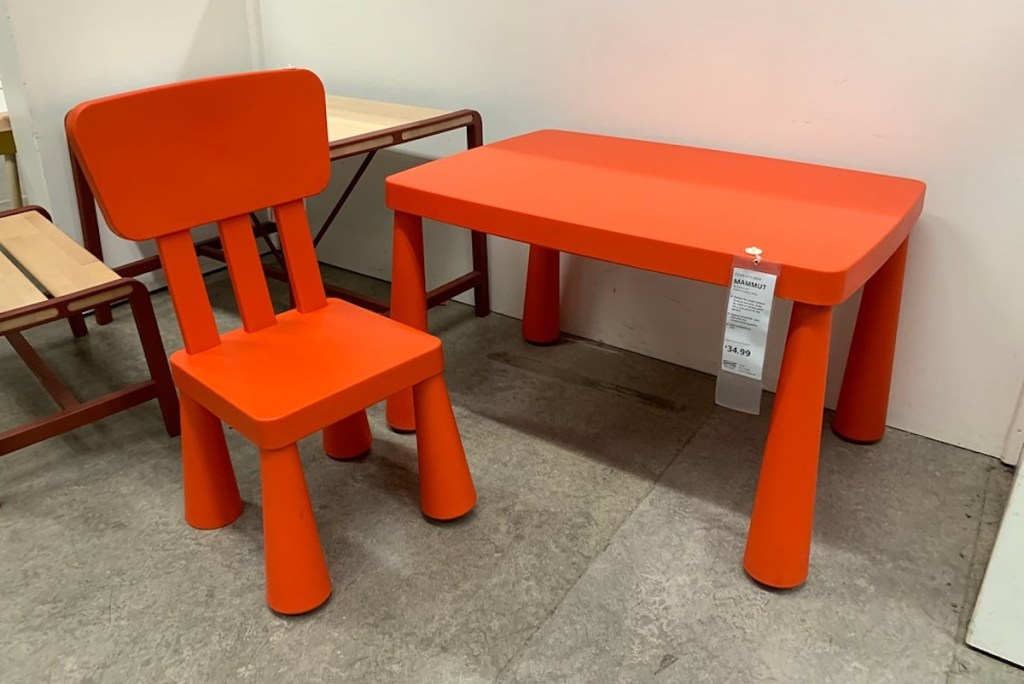 red kids size table and chair sitting on concrete floor in store
