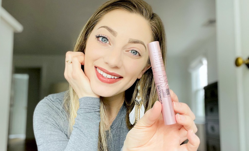 woman holding makeup in hand with one eye wearing best mascara