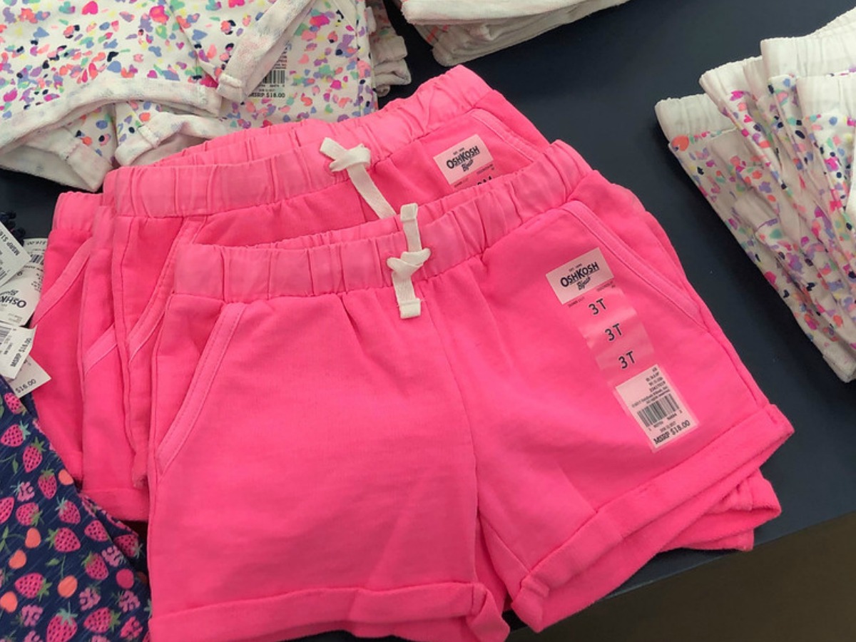 several pairs of oshkosh girls pink shorts on table in store