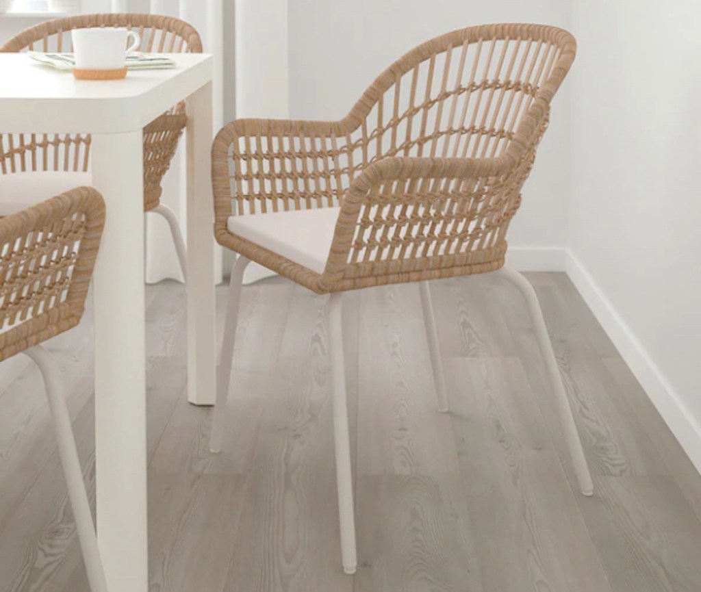 rattan chair with white cushion and legs sitting at dining room table