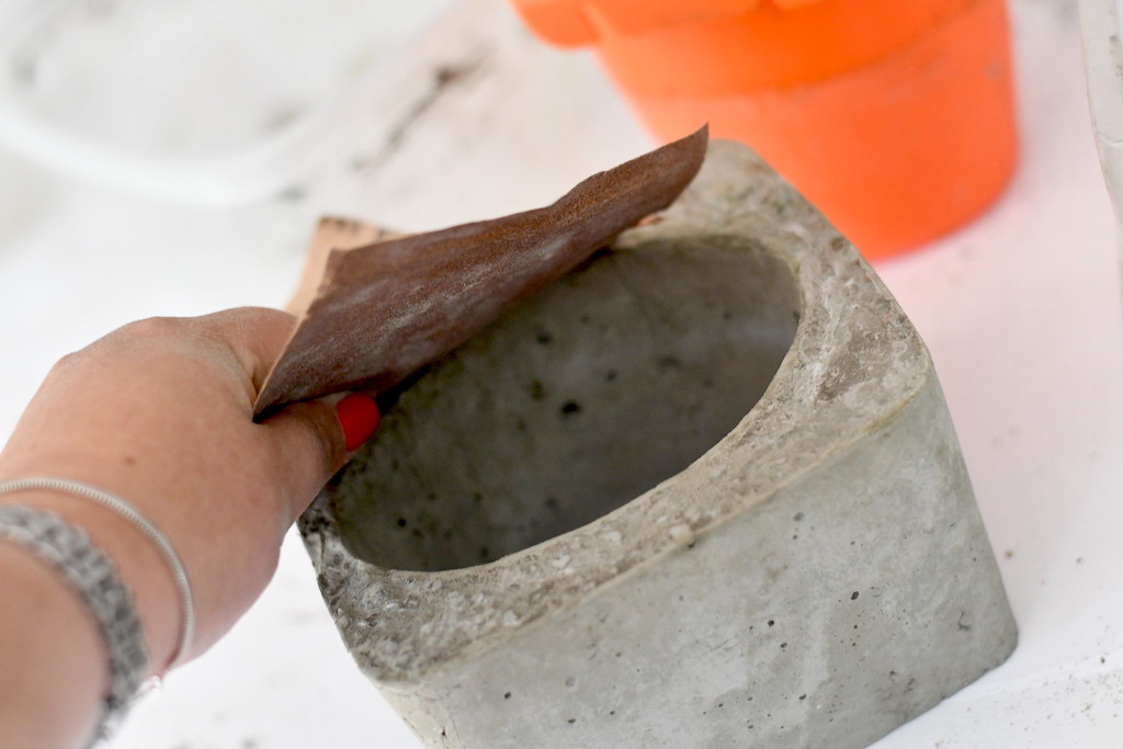 rubbing sandpaper on DIY concrete planter 
