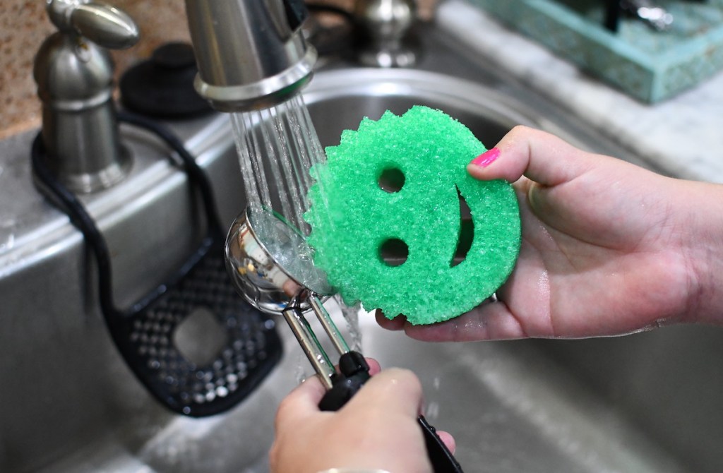 hand holding a green smiley face sponge and ice cream scoop