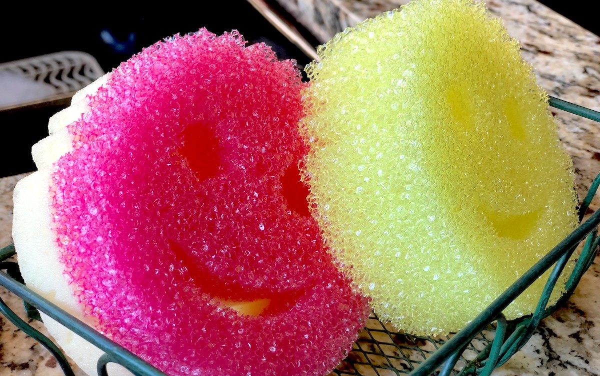 Pink and yellow smiley face scrub daddy sponges sitting in tray