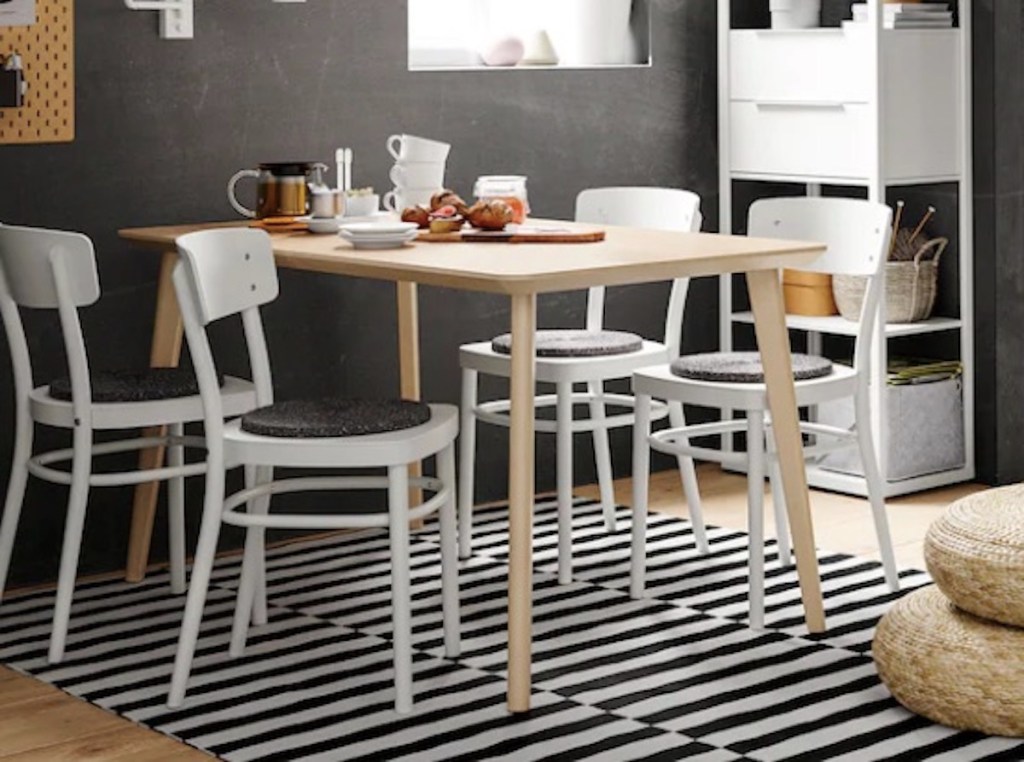 wood table in dining room with white chairs and black and white stripe rug